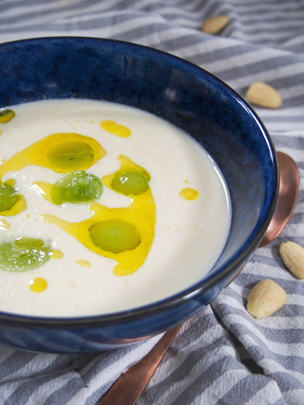 side view of bowl of ajo blanco topped with grapes and olive oil