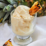glass with grilled pineapple ice cream garnished with slice of pineapple
