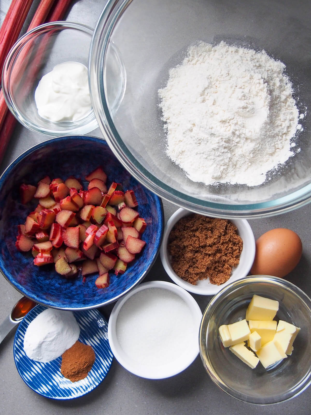 ingredients for rhubarb muffins bowls with flour, rhubarb, butter, sugar, yogurt and butter
