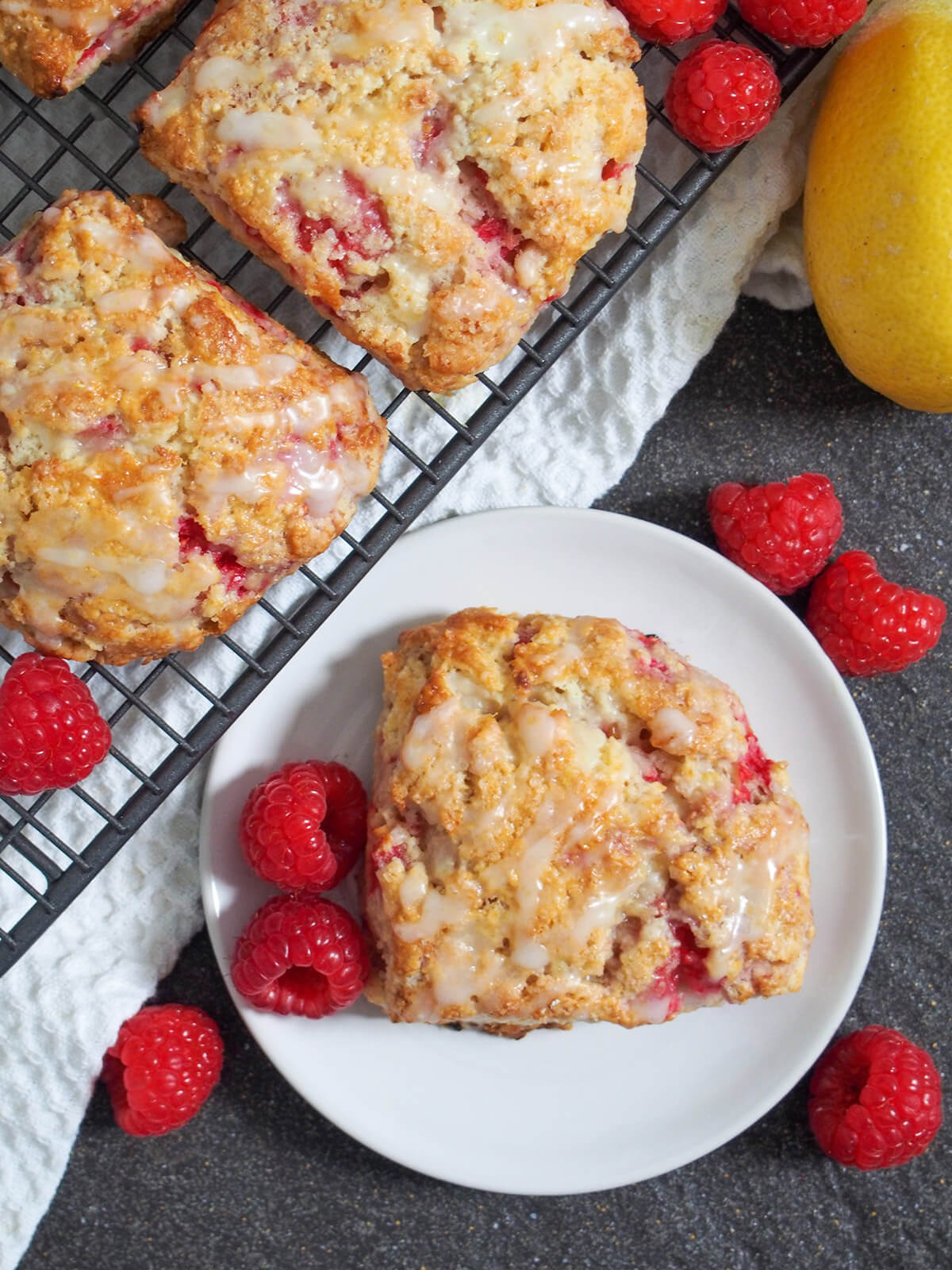 overhead view of raspberry scone on plate with cooling rack with more on