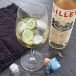 glass of lillet spritz with cucumber in glass and bottle of lillet to side