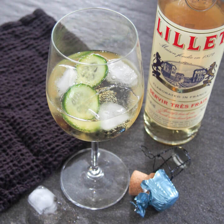 glass of lillet spritz with cucumber in glass and bottle of lillet to side