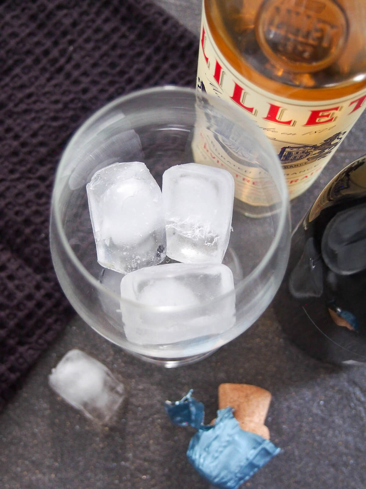 ice in glass and bottle of Lillet to side