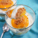 mango cheesecake parfait with spoonful held over glass