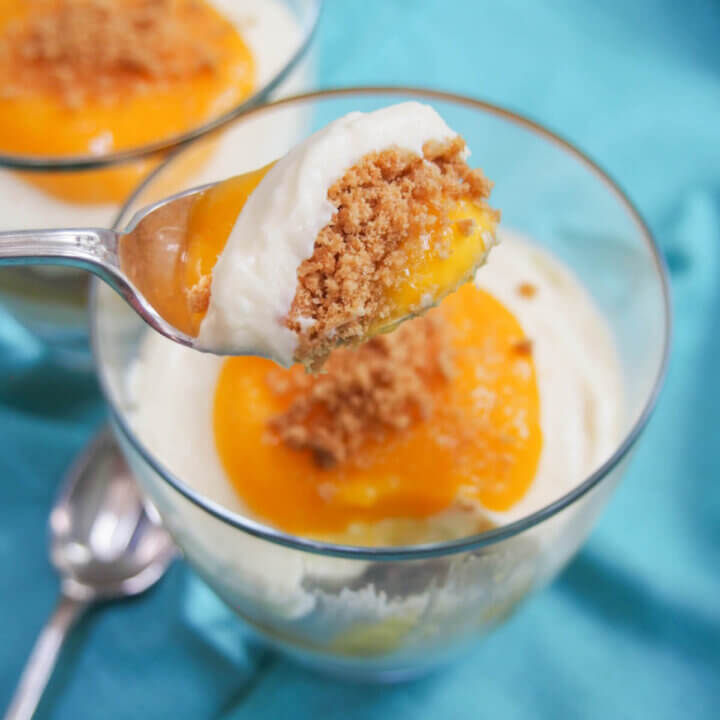 mango cheesecake parfait with spoonful held over glass