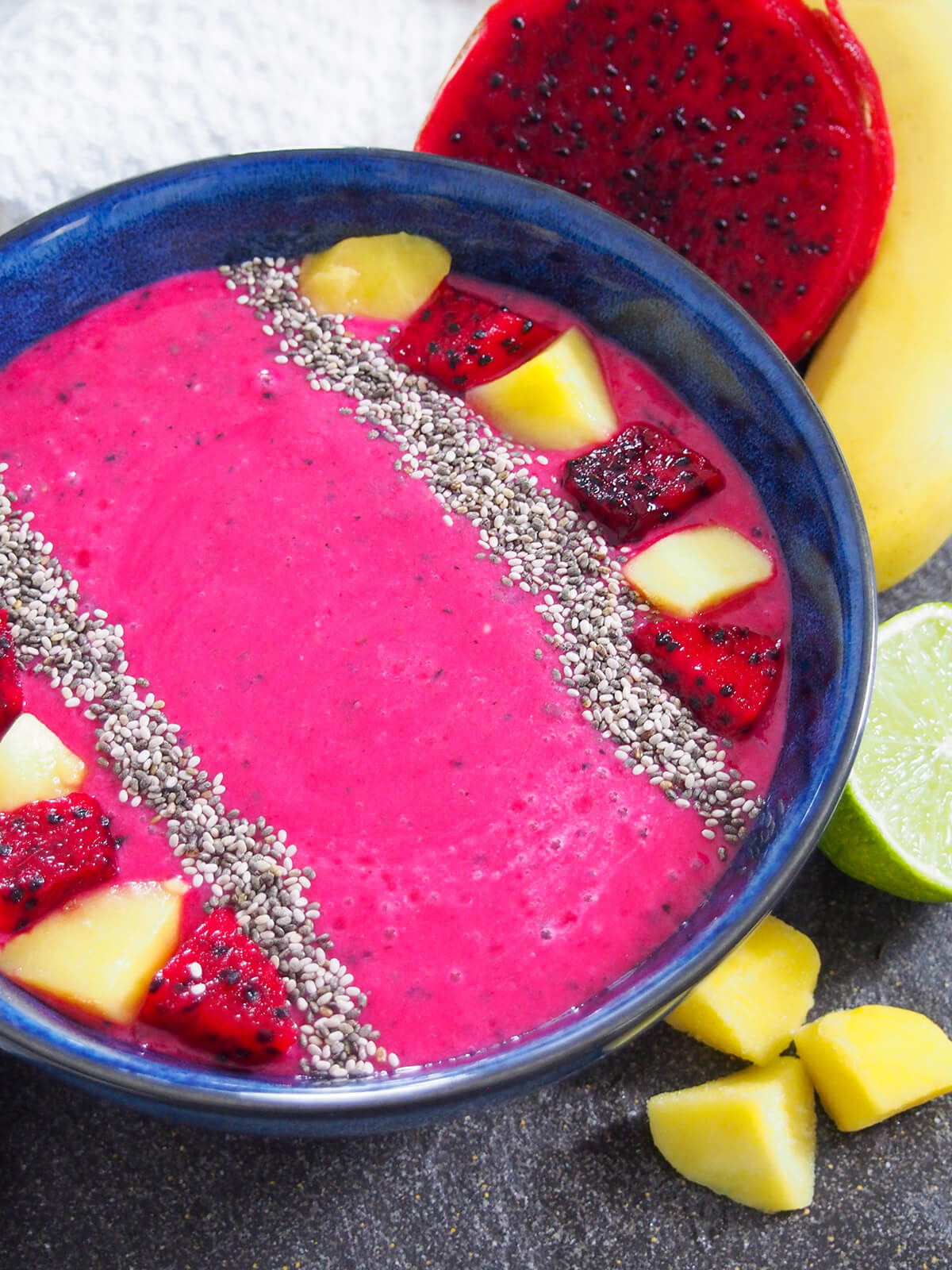 mango dragon fruit smoothie viewed from front with fruits beside bowl
