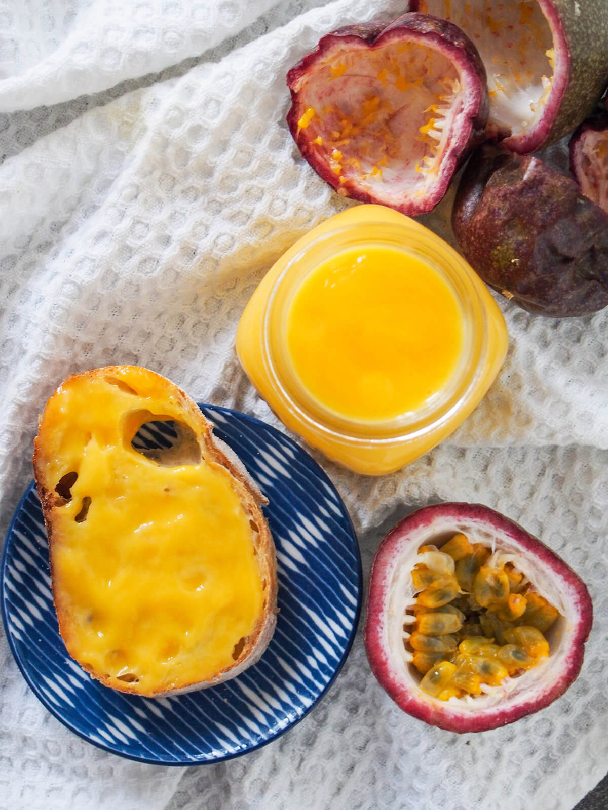 jar of passion fruit curd from overhead with curd-covered piece of bread to side