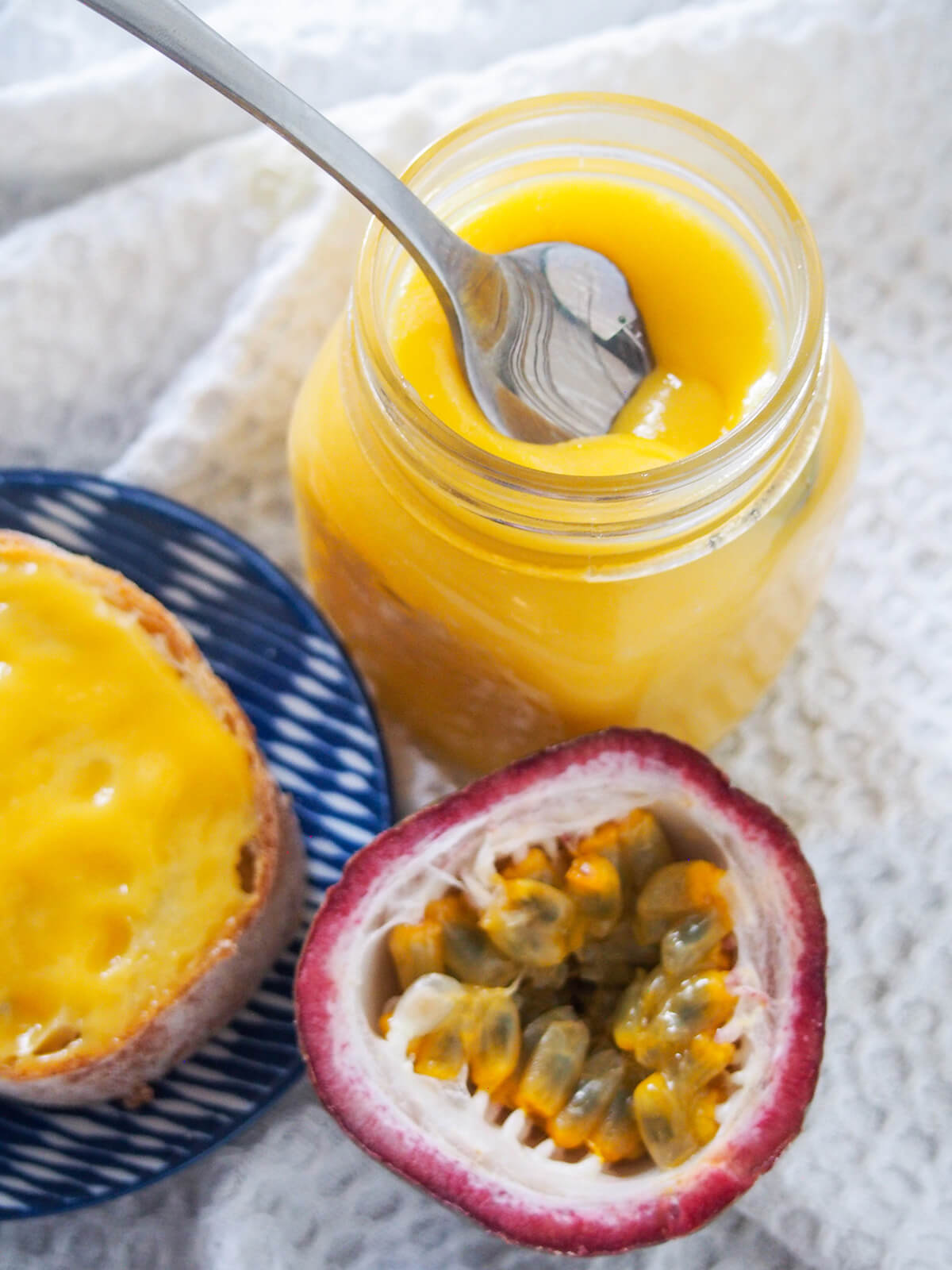 jar of passion fruit curd with spoon in it and cut passion fruit in front