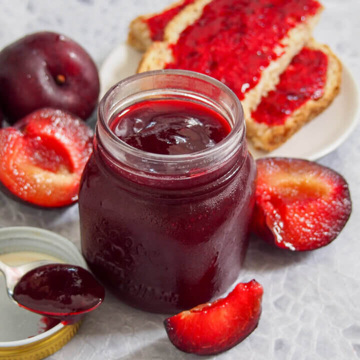 jar of plum jam with pieces of plum to side