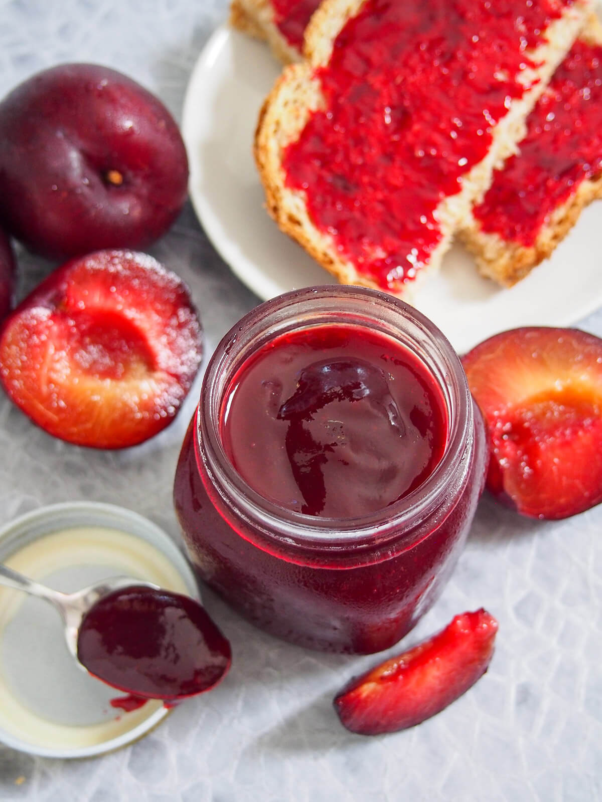 jar of jam from overhead with plums to side