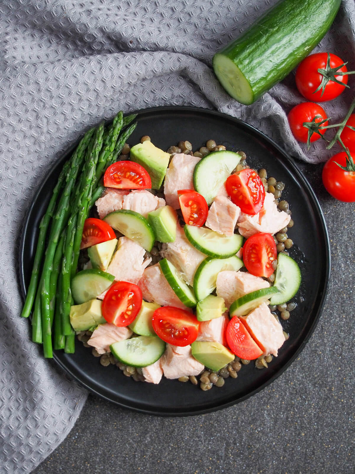 plate of poached salmon salad from overhead with cucumber and tomatoes to side