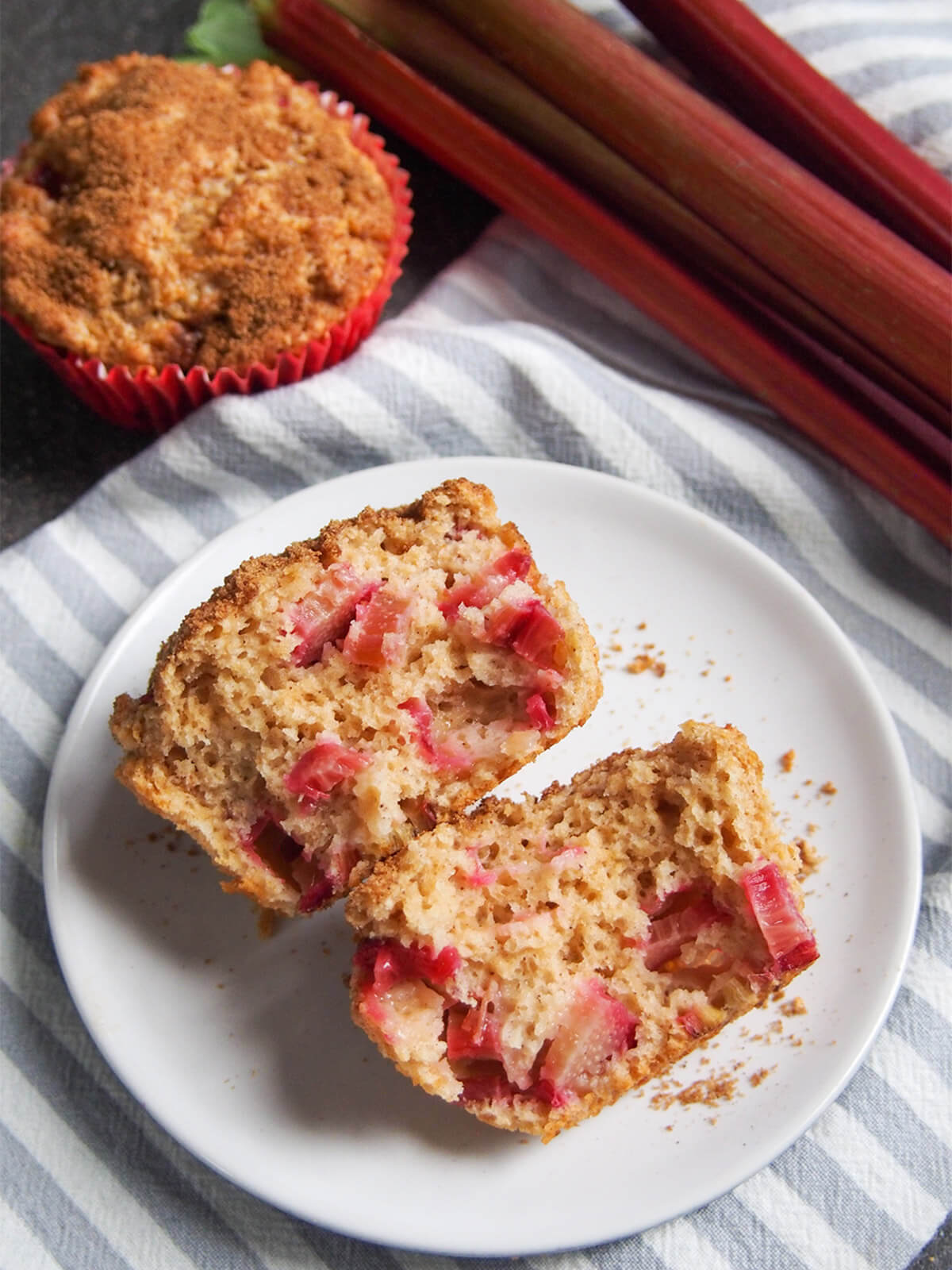 These rhubarb muffins are a delicious combination of tart bursts of rhubarb in a soft muffin and warm sweet cinnamon sugar topping. They make a great coffee time snack, or really any time. split open rhubarb muffin showing chunks of rhubarb inside