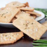 one cracker balanced on plate of whole wheat olive oil crackers