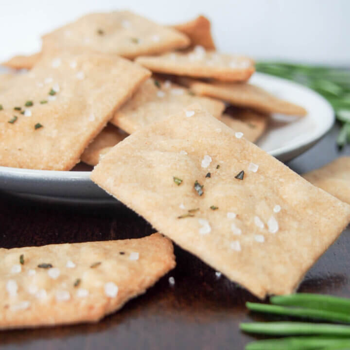one cracker balanced on plate of whole wheat olive oil crackers