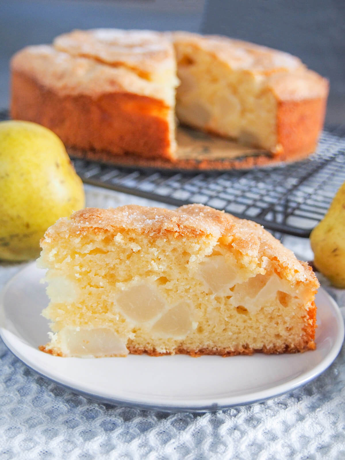slice of pear cake on plate with rest of cake behind