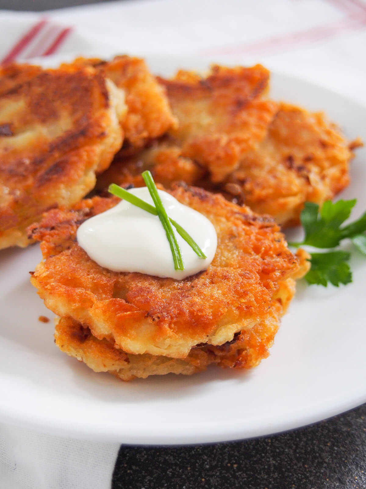 two potato pancakes stacked with sour cream on top, more behind