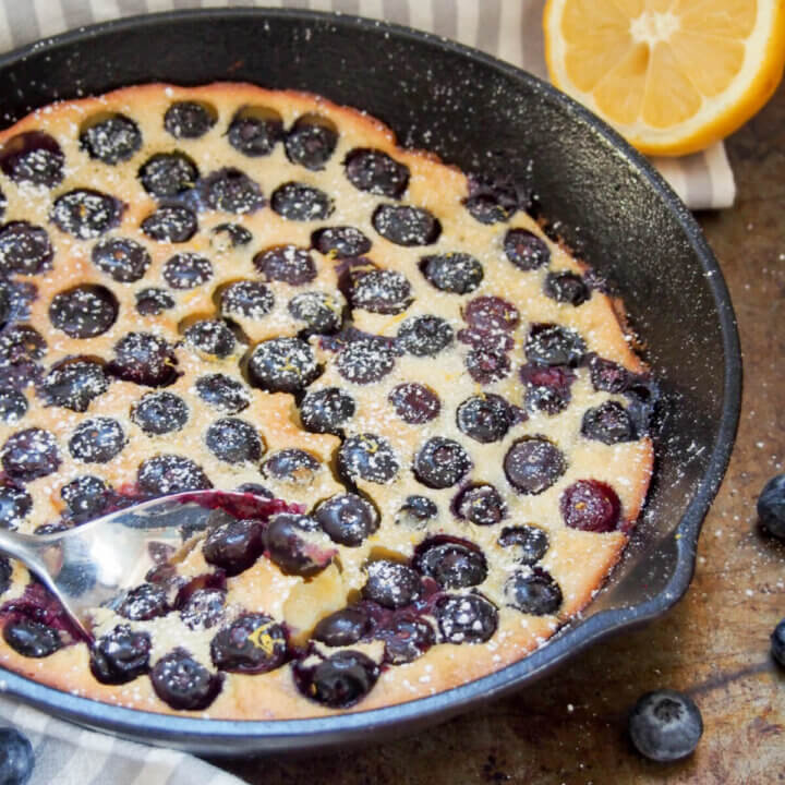spoon in skillet of blueberry clafoutis