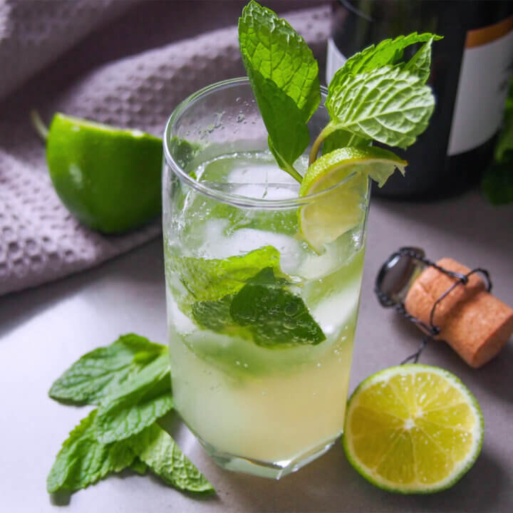glass of champagne mojito garnished with mint and lime slice