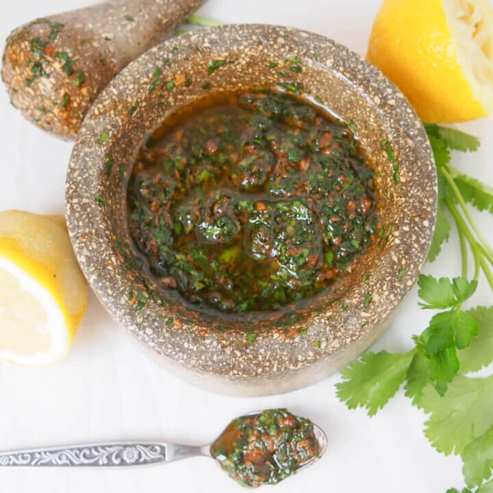 pestle and mortar with chermoula sauce and spoon with sauce to bottom