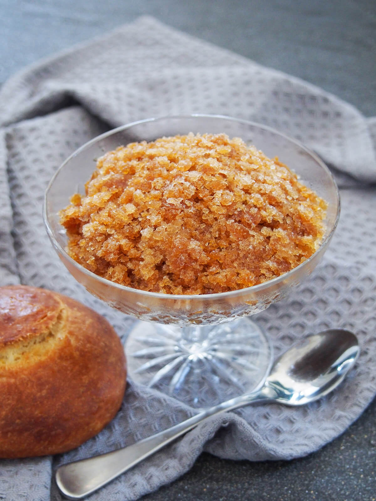 glass of coffee granita with spoon under glass and brioche to side