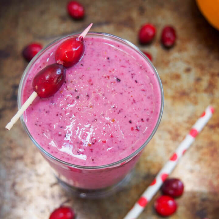 cranberry smoothie viewed from overhead with cranberries on stick as garnish