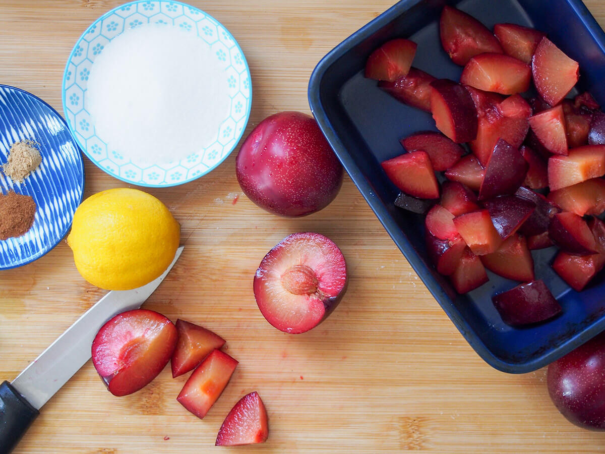 cutting plums and placing in baking dish with lemon, cornstarch and spices to side