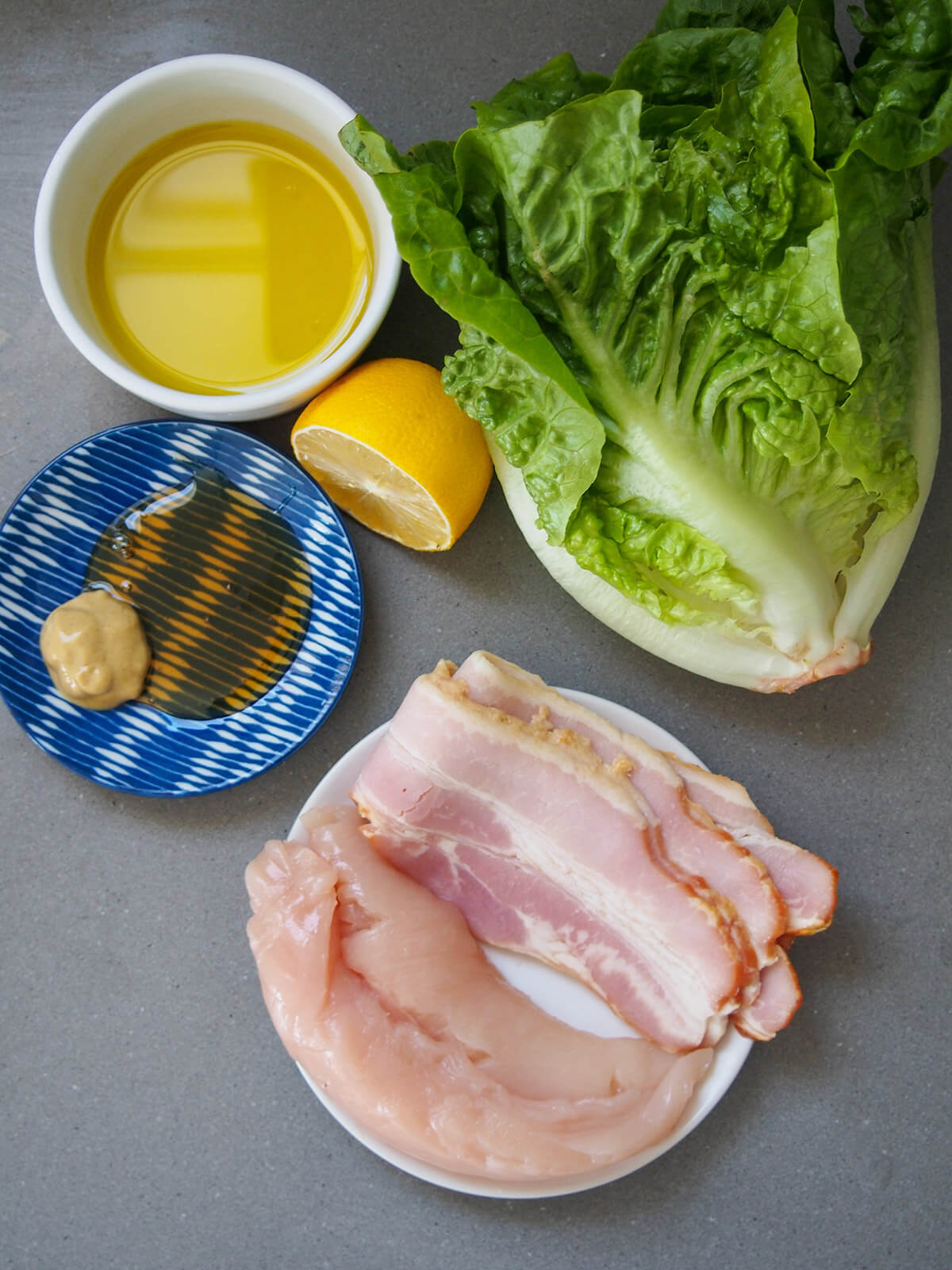 plate with chicken and bacon with oil, lettuce, lemon, honey and mustard to side