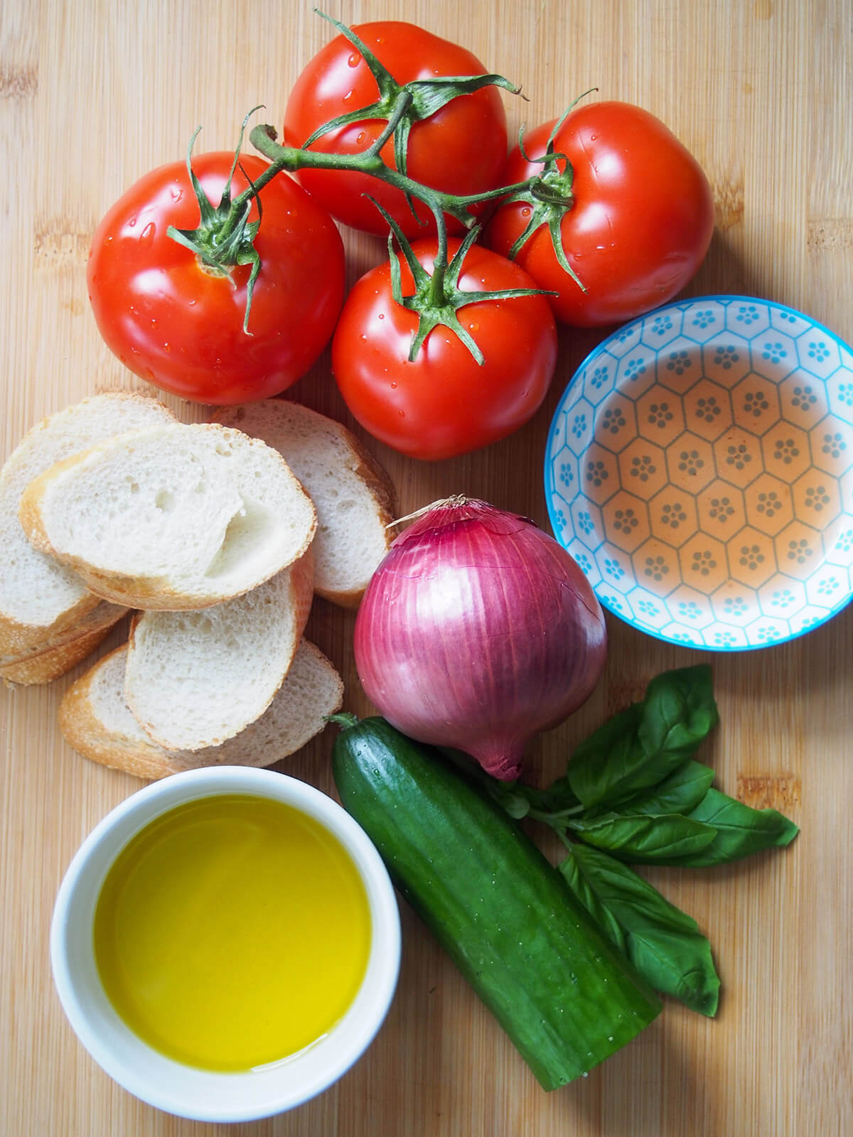 tomatoes, slices of bread, red onion, cucumber, basil and bowls with olive oil and vinegar