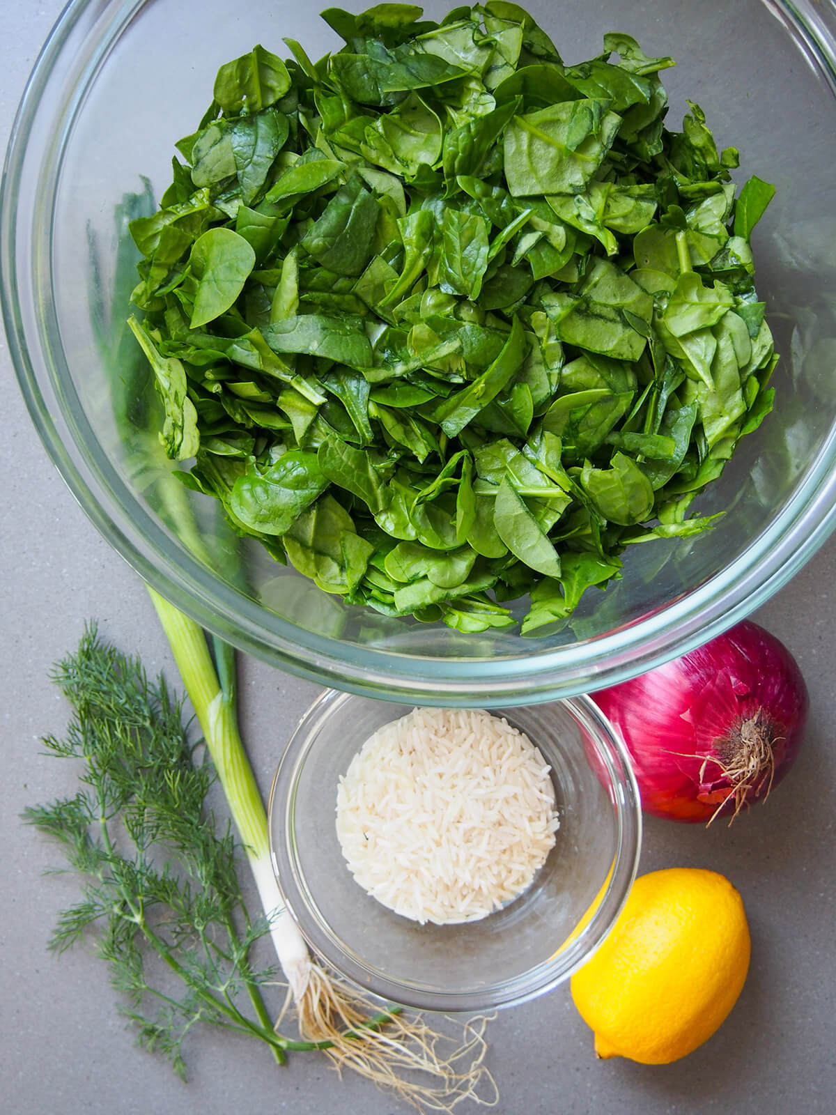 bowl of spinach, bowl with rice below and onion, lemon and dill to sides