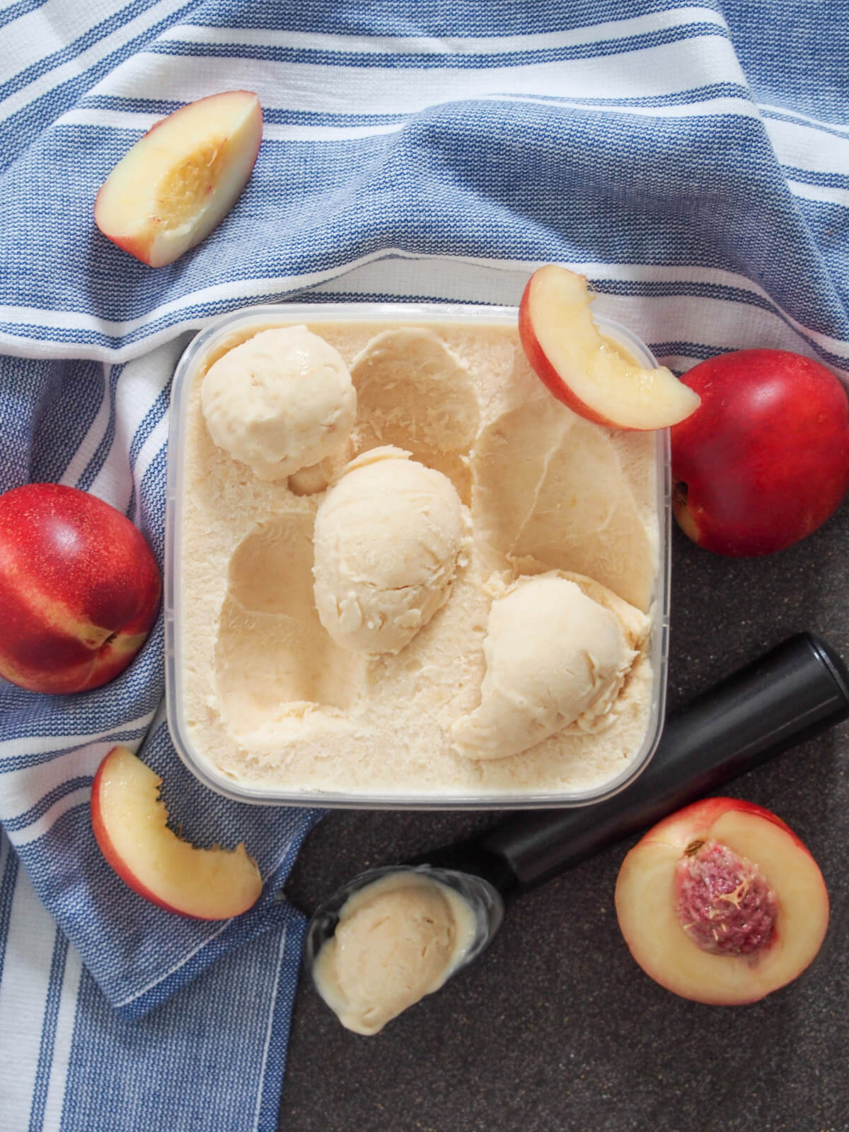 tub of nectarine ice cream with scoop with some ice cream dripping below container