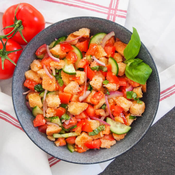 bowl of panzanella salad from overhead with tomatoes to side of bowl