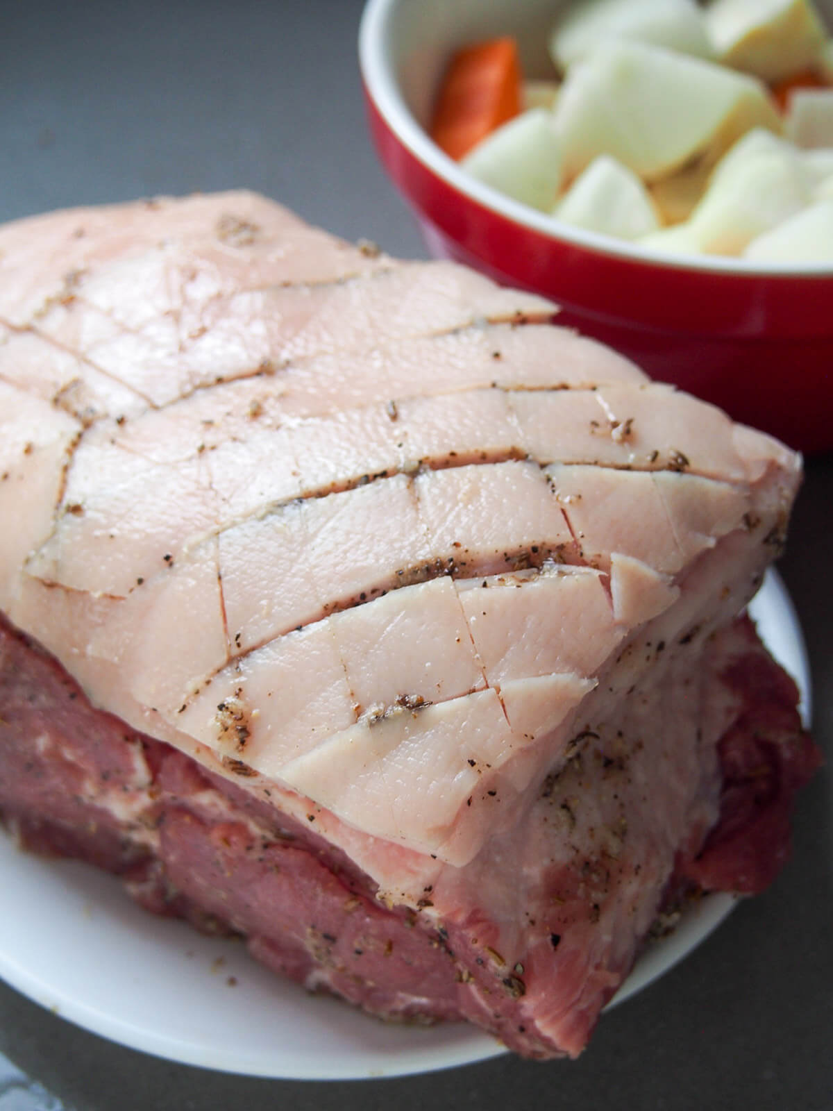 piece of pork with skin scored and rub rubbed into slits