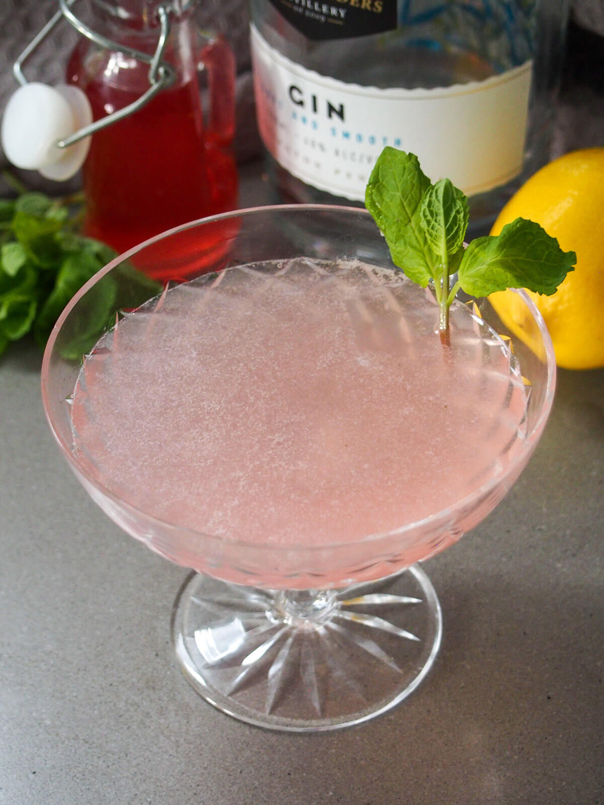 looking into glass with pink tinged drink and mint sprig garnish