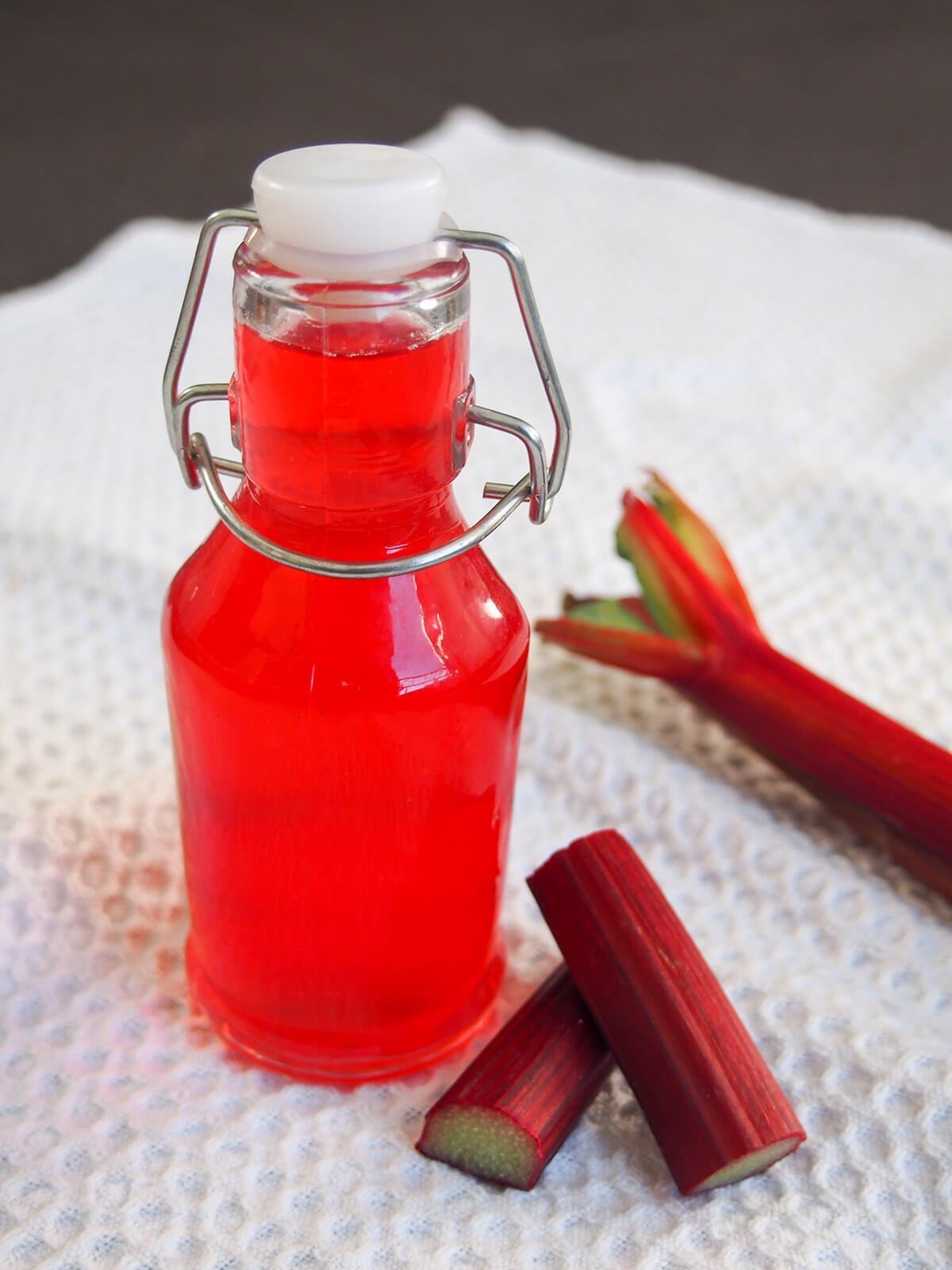 bottle of rhubarb syrup with pieces of rhubarb to side