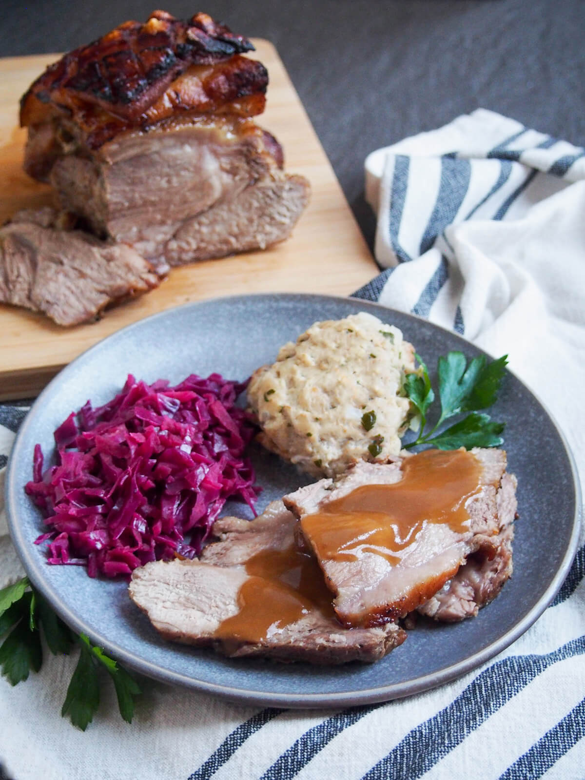 plate of Schweinebraten - German pork roast - with sides on plate and rest of roast on board behind