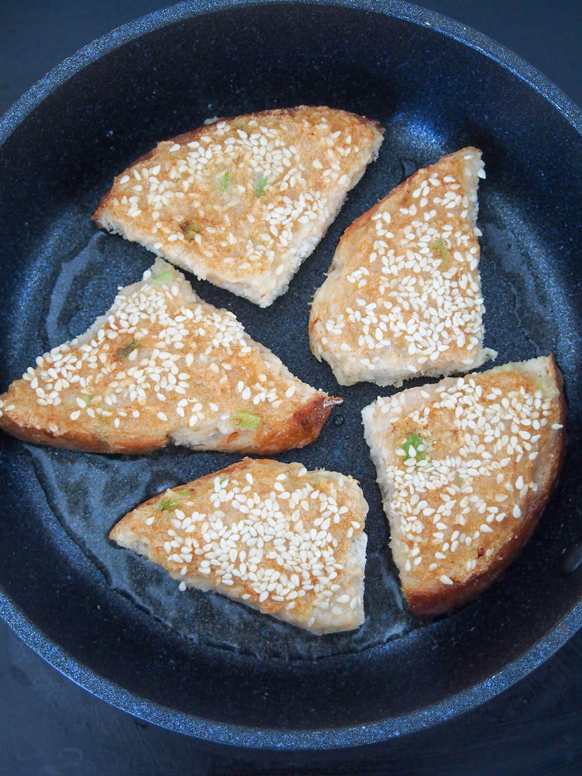 cooking second side in skillet showing sesame seeds on top