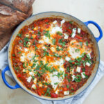 shakshuka with meat in dish with sliced bread above dish
