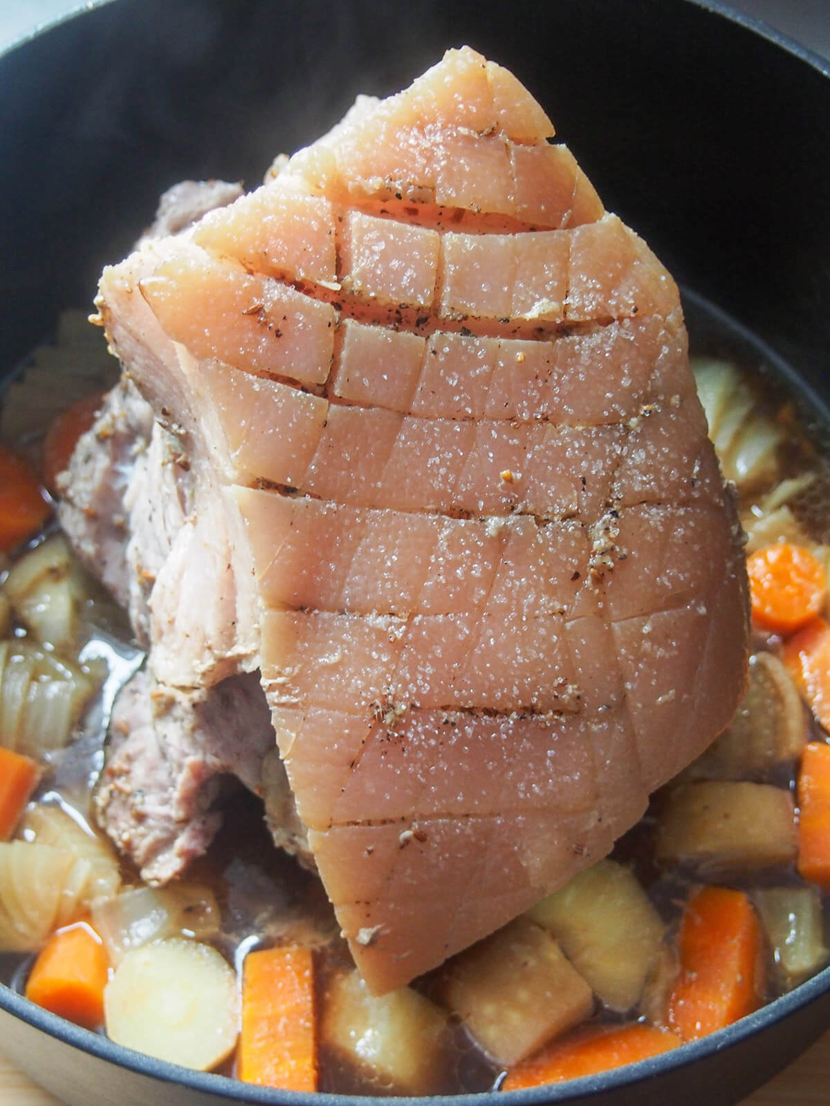 pork in pot with vegetables skin side up part way through cooking