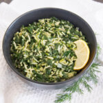 bowl of spanakorizo with slice of lemon to side