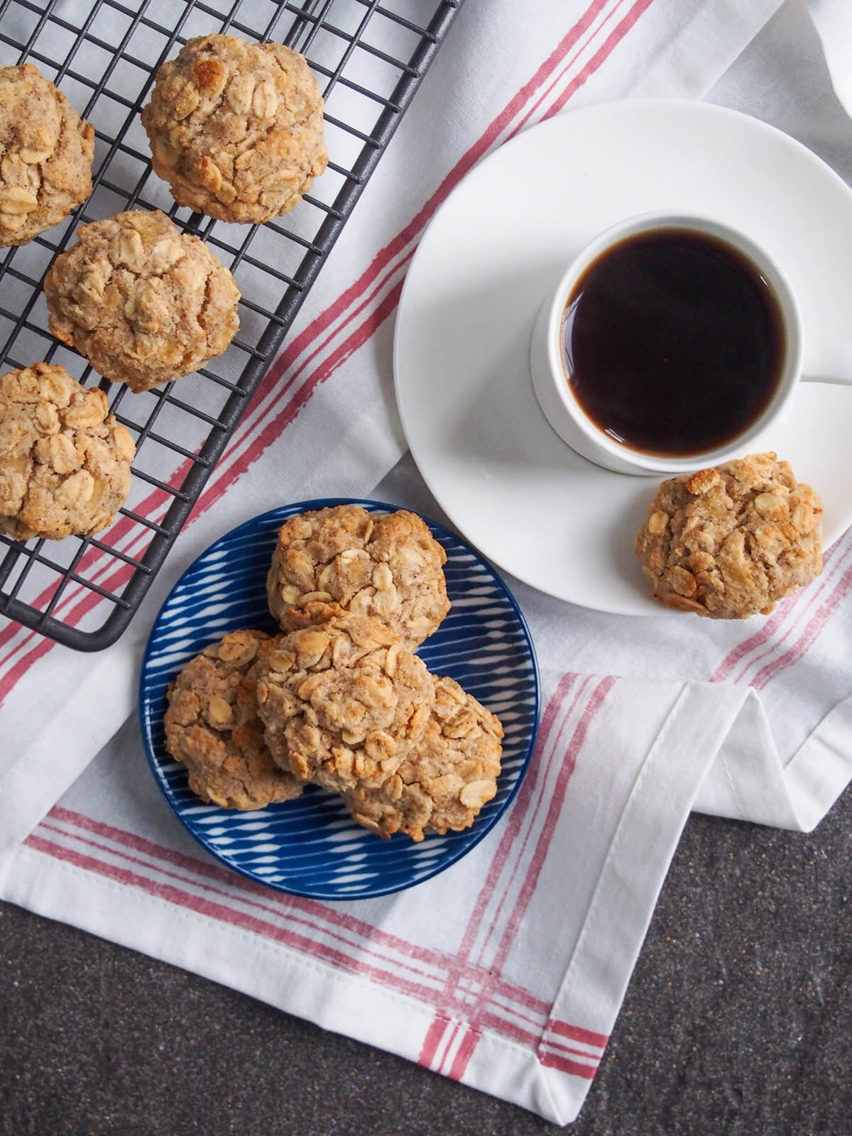 These spiced maple oatmeal cookies are perfect to enjoy some fall flavors, but equally delicious any time. With apple, oats and warm spices, they're deliciously sweet, even being refined sugar free. plate of spiced maple oatmeal cookies with one on saucer under cup and more on cooling rack