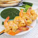 skewers of tandoori shrimp with chutney behind