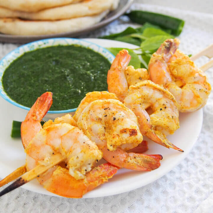 skewers of tandoori shrimp with chutney behind