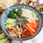 bowl of vegetarian bibimbap with the various vegetables in piles over the rice underneath