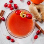 glass of warm cranberry cocktail viewed form overhead with cranberries on stick as garnish
