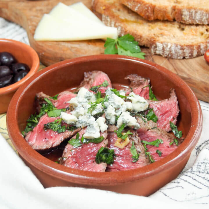 dish with white wine marinated steak topped with blue cheese