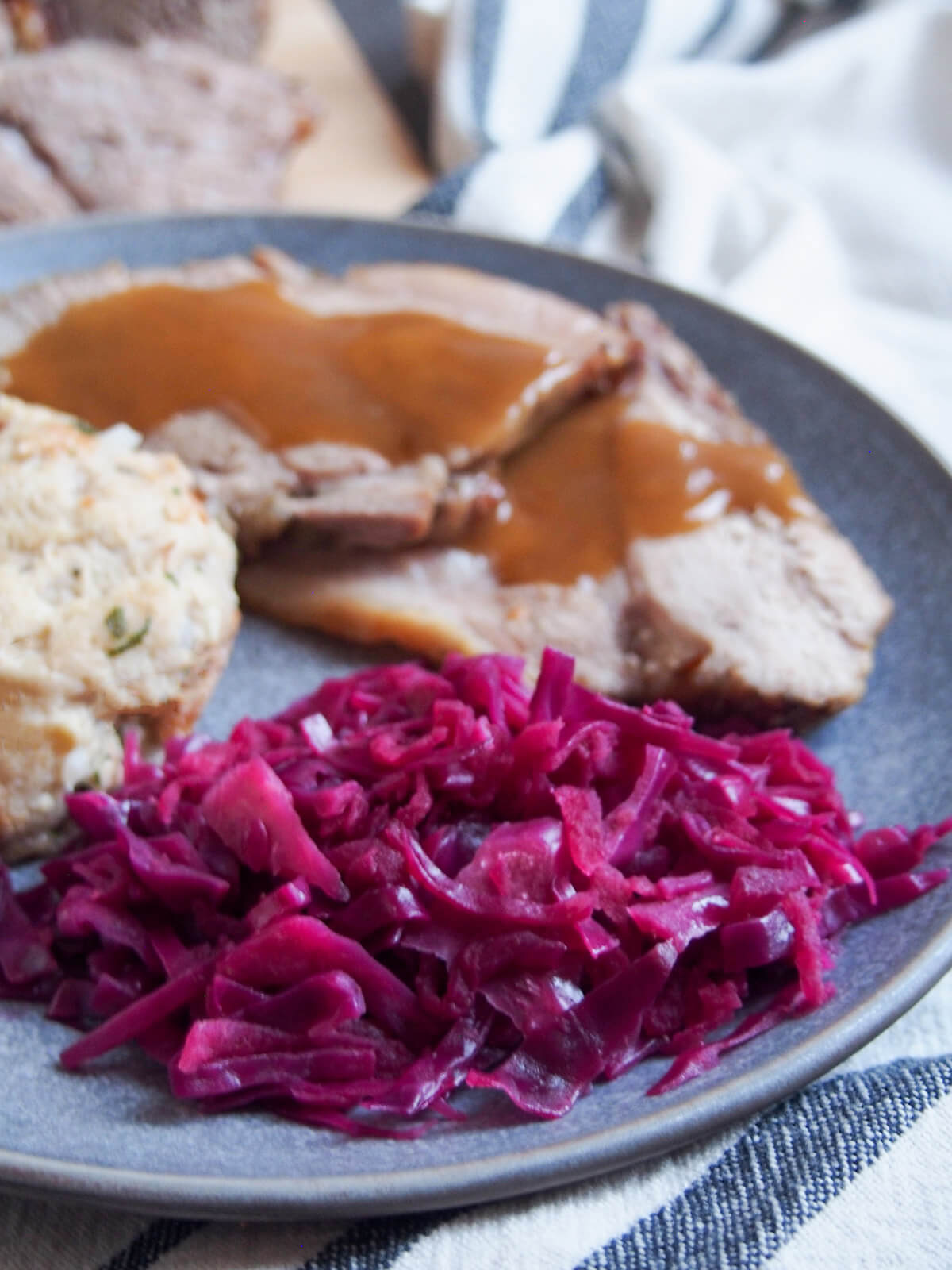 plate with German braised red cabbage in front of pork with gravy over it