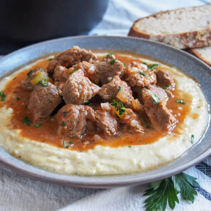Turkish lamb stew with eggplant puree underneath with bread behind