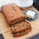 Irish brack fruit loaf with slices to front and butter on plate to side
