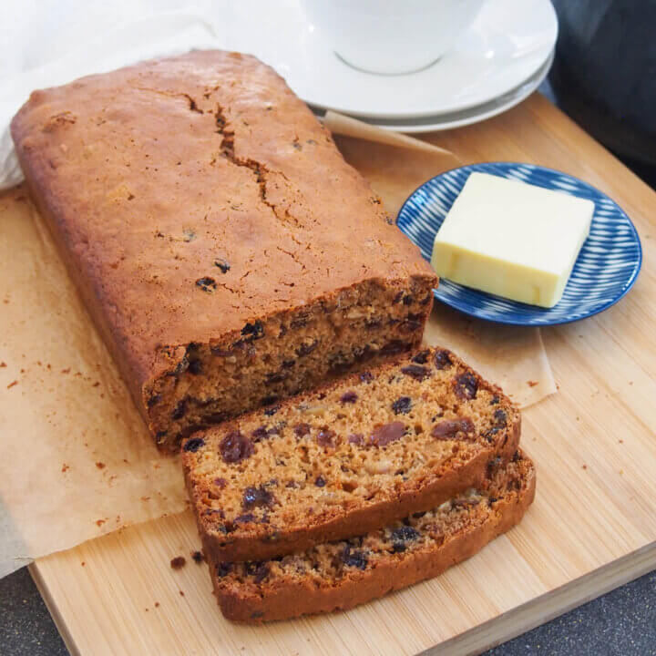 Irish brack fruit loaf with slices to front and butter on plate to side
