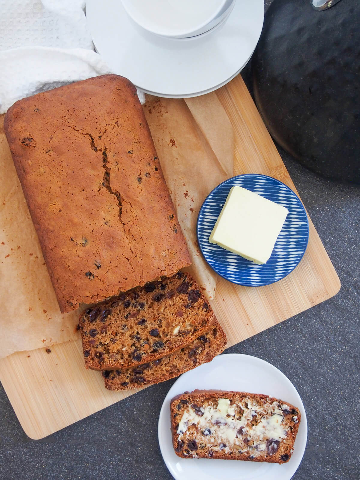 Irish brack is a traditional fruit loaf where the fruit is soaked in sweet tea before making a quick bread. It's a perfect treat with your tea/coffee. Irish brack fruit loaf from overhead with cups and kettle to side
